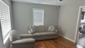 A living room with a sofa, a chair, and a window with blinds. - Holy Holt of Lexington nc (Lexington)