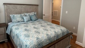 A bedroom with a bed, a nightstand, a door, and a hallway. - Holy Holt of Lexington nc (Lexington)
