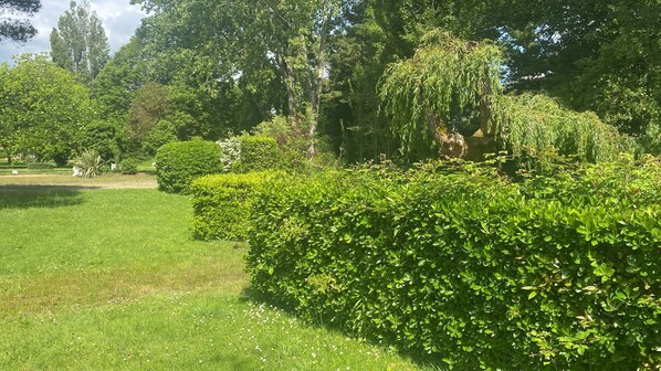 A well-maintained garden with neatly trimmed hedges and a variety of trees.