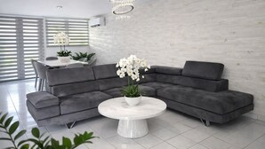 A modern living room with a grey sectional sofa, a white marble coffee table, and a chandelier.