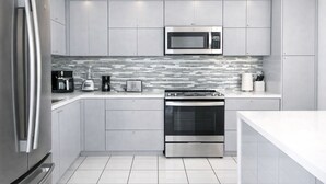 A modern kitchen with stainless steel appliances, a microwave, and a tiled backsplash.