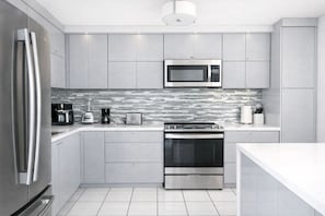 A modern kitchen with stainless steel appliances, a microwave, and a tiled backsplash.