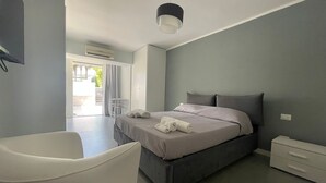 Un dormitorio moderno con cama, mesita de noche y una silla blanca.