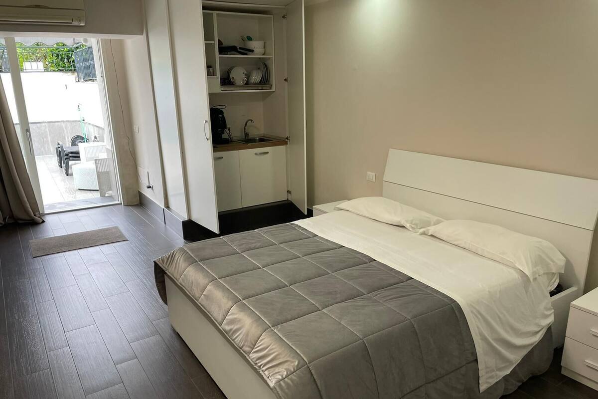 Une chambre comprenant un lit, une table de chevet, une armoire intégrée et un coin cuisine.