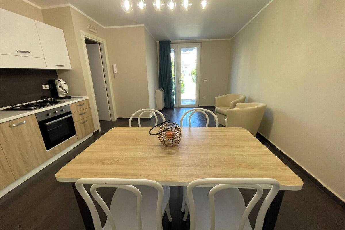 Une cuisine moderne avec un coin repas, des chaises blanches et une table en bois.
