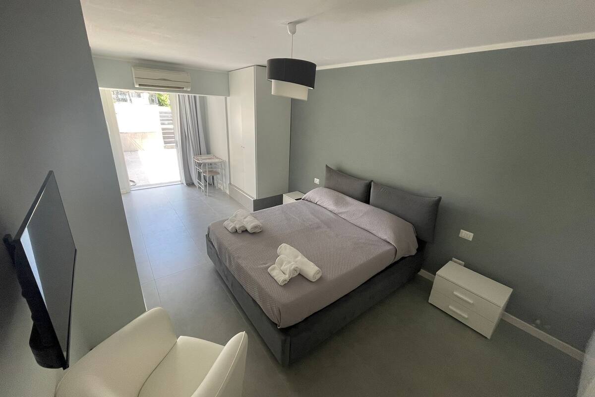 Une chambre à coucher moderne avec un lit, une chaise, un bureau et un téléviseur.