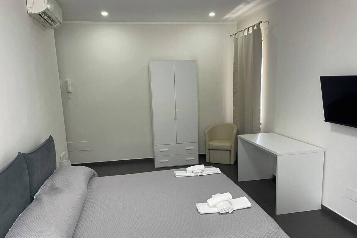Une chambre d’hôtel équipée d’un lit, d’un bureau, d’une chaise, d’une armoire et d’un téléviseur.