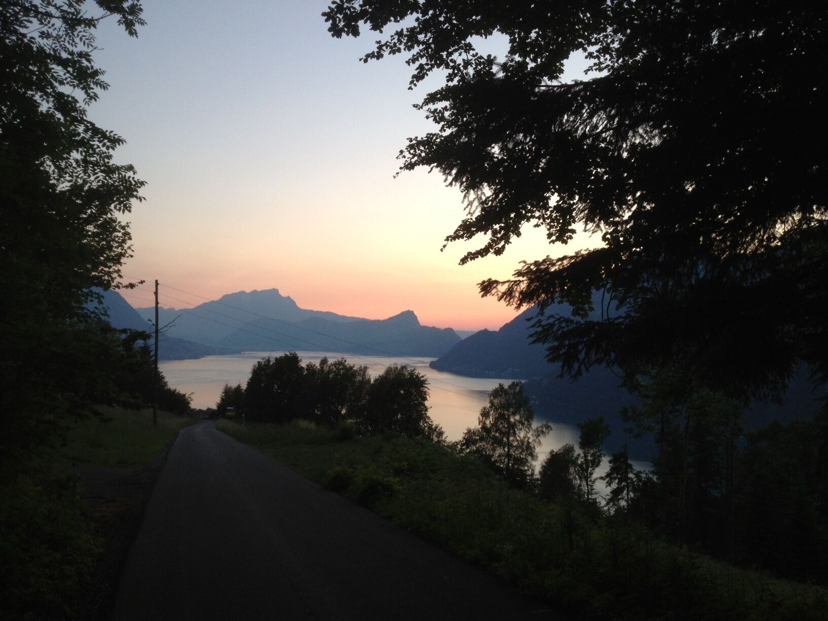 Eine Straße führt zu einem Gewässer, im Hintergrund Berge.