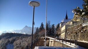 A snow-covered mountain path with a street lamp and a building with a steep incline. - Guest apartment with breathtaking lake view in the Swiss mountains (Seelisberg)