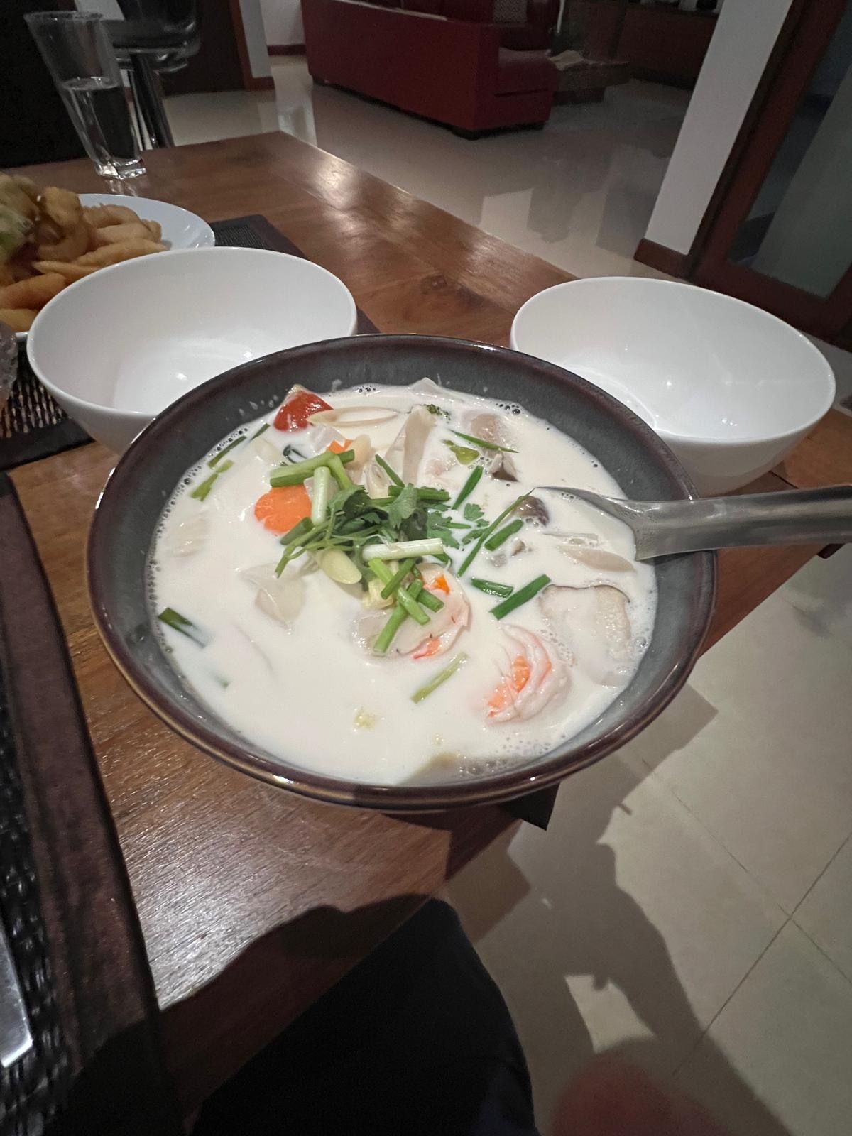 Un tavolo da pranzo con una ciotola di zuppa, un piatto di pane e un bicchiere d'acqua.