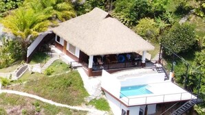 A thatched-roof house with a swimming pool and a separate building with a white exterior. - Casa Ceibosito (Tres Rios de Osa)