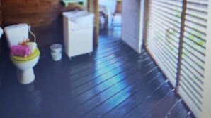 A corridor with a tiled floor, a toilet, and a counter.
