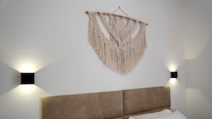 A bedroom with a bed, a headboard, and a macrame wall hanging.