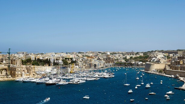 A harbor with numerous boats docked, surrounded by a densely built urban area with historical architecture.