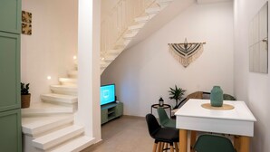 A modern interior with a staircase, a dining area, and a television.