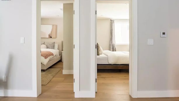 A hallway leading to two bedrooms with a bed, a nightstand, and a bedside table. - 67 Alta Vista Way (Daly City)