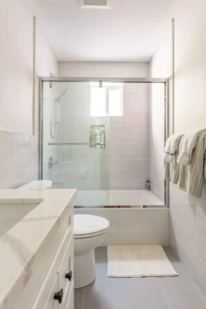 Enjoy a refreshing shower in the bathroom, featuring a glass-enclosed shower, standalone toilet, and bathtub with a glass door.
