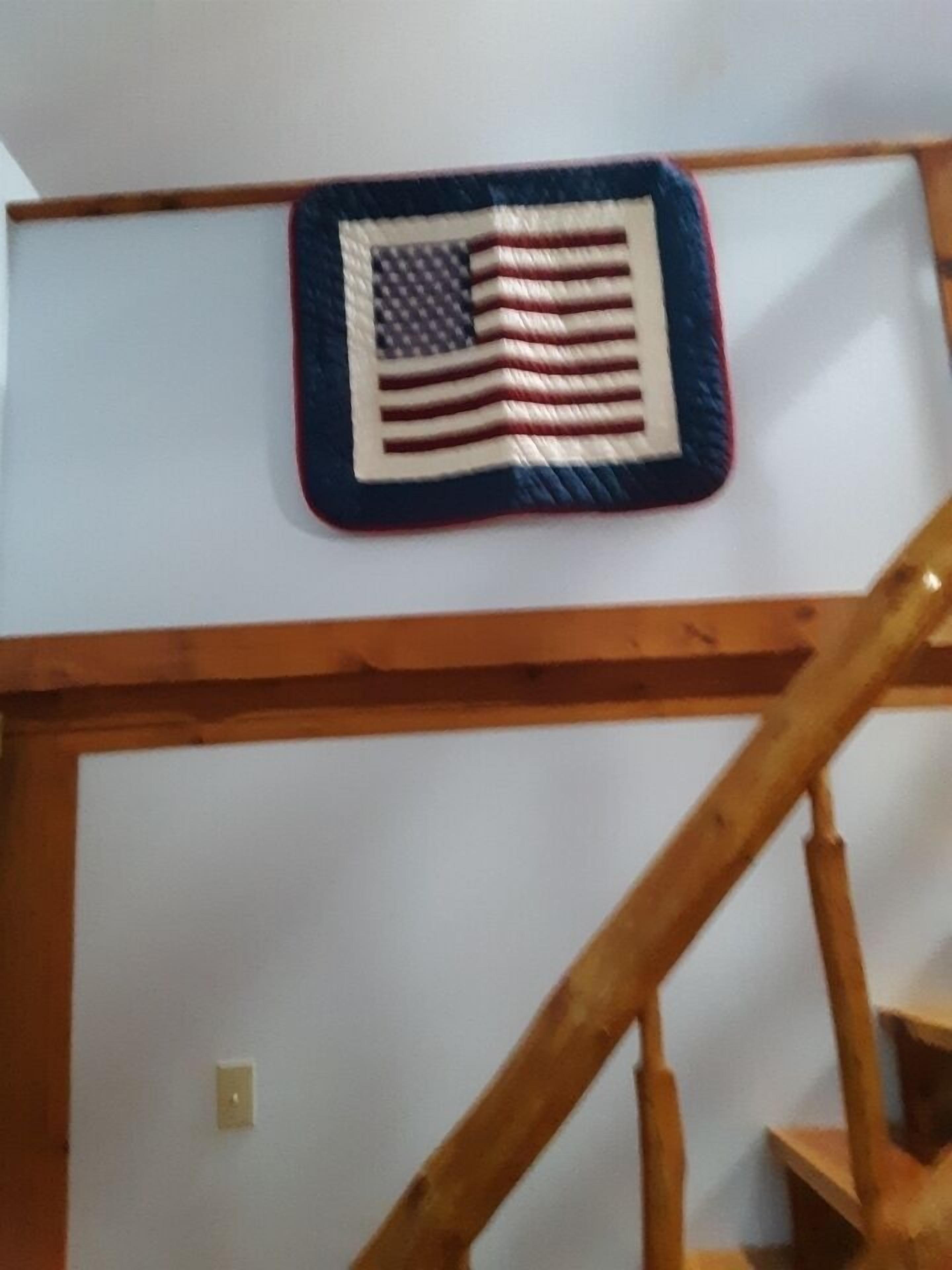 A staircase with a wooden handrail and a wall-mounted American flag decoration.