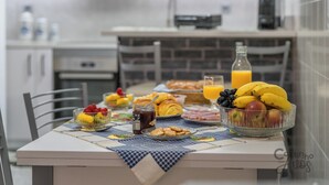 Une table de petit-déjeuner avec des croissants, des fruits et une bouteille de jus d’orange.