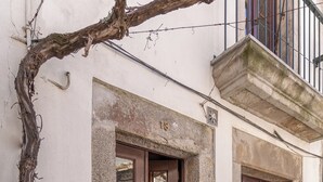 Une femme entre dans un bâtiment par une porte en bois dont le bas est en pierre.