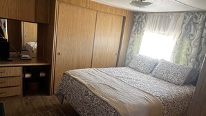 Un dormitorio pequeño con cama, escritorio y armario.