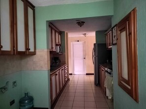 Een koelkast, een magnetron, kookgerei, borden en bestek