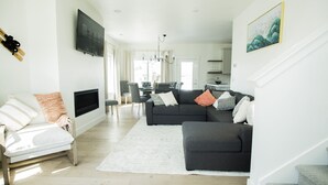 Een moderne woonkamer met een bank, fauteuil en een flatscreen televisie.