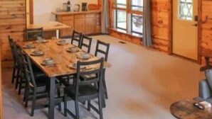 A spacious dining area with a wooden table and chairs, a ceiling fan, and a rustic wooden interior.