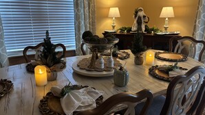 Een eettafel gedekt met kaarsen, een kerstboom en feestdecoraties.