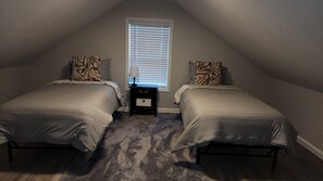 A small, dimly lit room with two beds, a nightstand, and a window with blinds. - Waterfront Home, 3 BR, 2 Bath, HOT TUB, Pet-Friendly, Fishing, Fire Pit
  (Murphy)