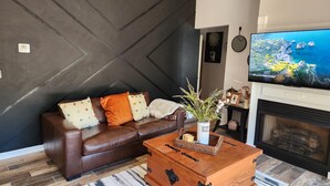 Un salon moderne avec un canapé en cuir marron, une table basse en bois et une cheminée.
