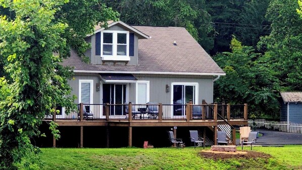 A two-story house with a deck, a covered patio, and a fenced backyard. - Waterfront Home, 3 BR, 2 Bath, HOT TUB, Pet-Friendly, Fishing, Fire Pit
  (Murphy)