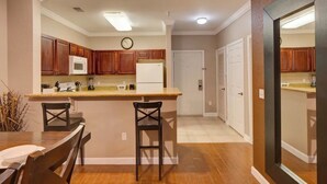 A modern kitchen with wooden cabinets, a central island, and a dining area with two chairs.