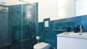 Een badkamer met een douchecabine van glas, een toilet en een wastafel met een spiegel erboven.