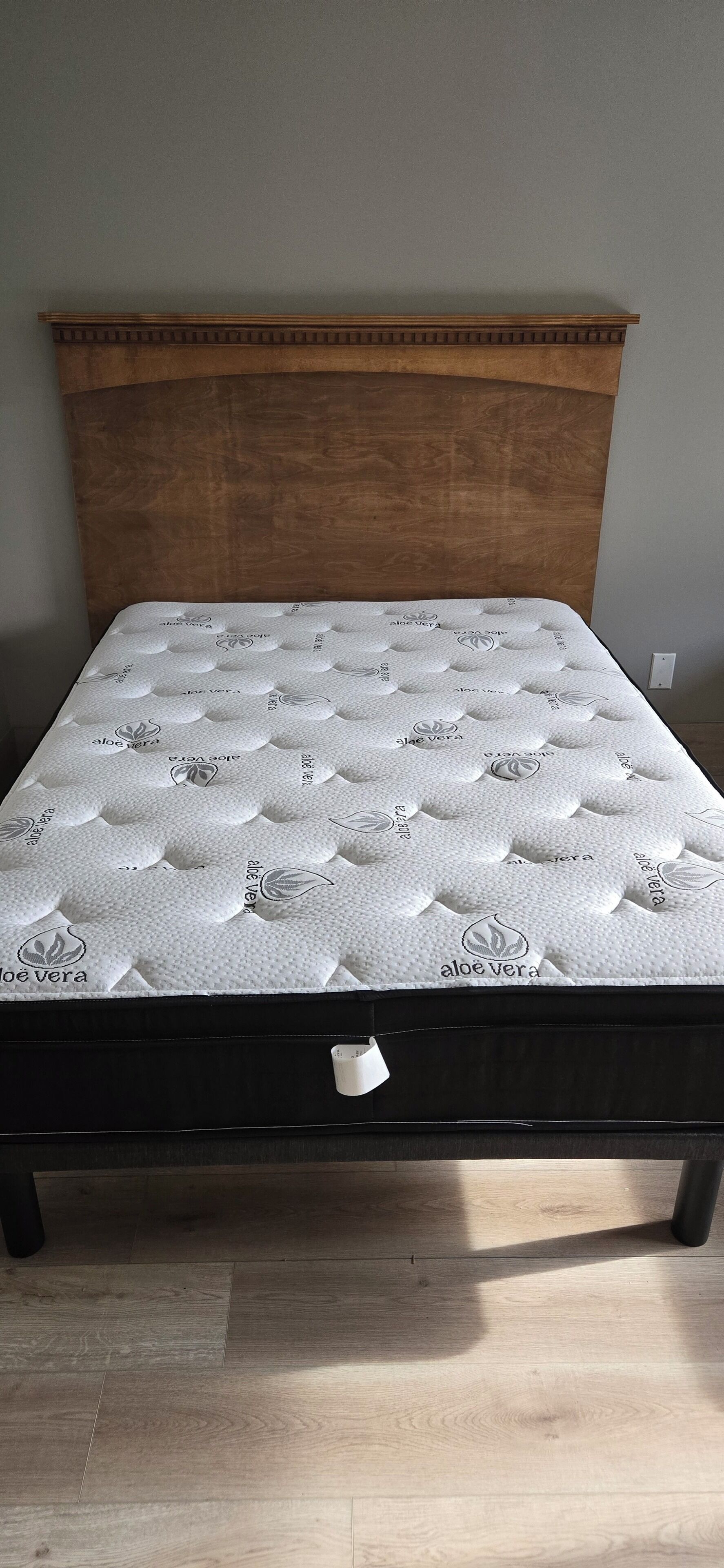 A bed with a wooden headboard and a mattress with a leaf pattern.
