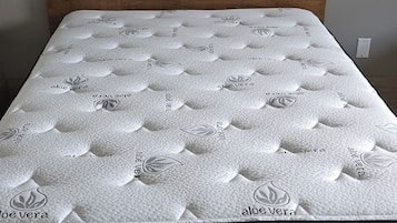 A bed with a wooden headboard and a mattress with a leaf pattern.