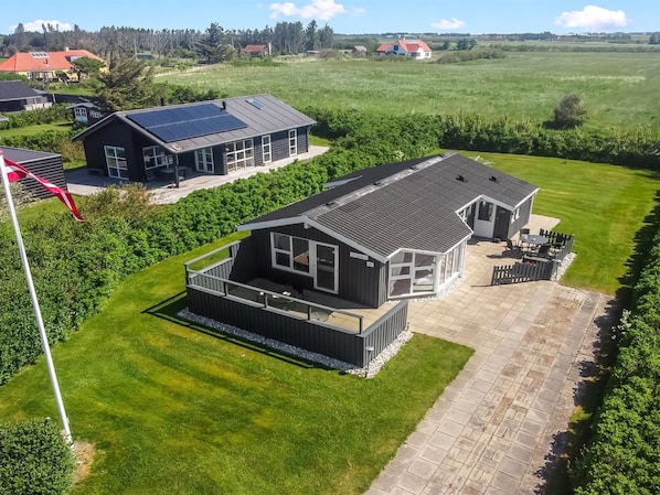 Una casa moderna con una terraza amplia, un garaje independiente y un césped cuidado.