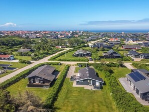 Un quartier résidentiel avec des maisons, de belles pelouses verdoyantes et une vue dégagée sur la mer.