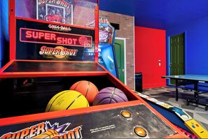 A basketball arcade game with multiple basketballs and a ping pong table in the background. - The Best Home's Resort Orlando (Kissimmee)