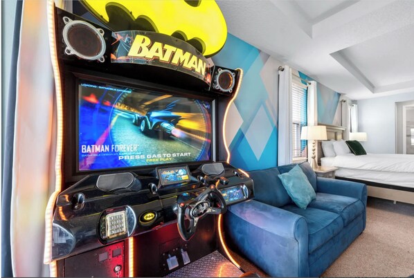 A gaming setup with a Batman Forever game, a blue couch, and a bed in the background. - The Best Home's Resort Orlando (Kissimmee)