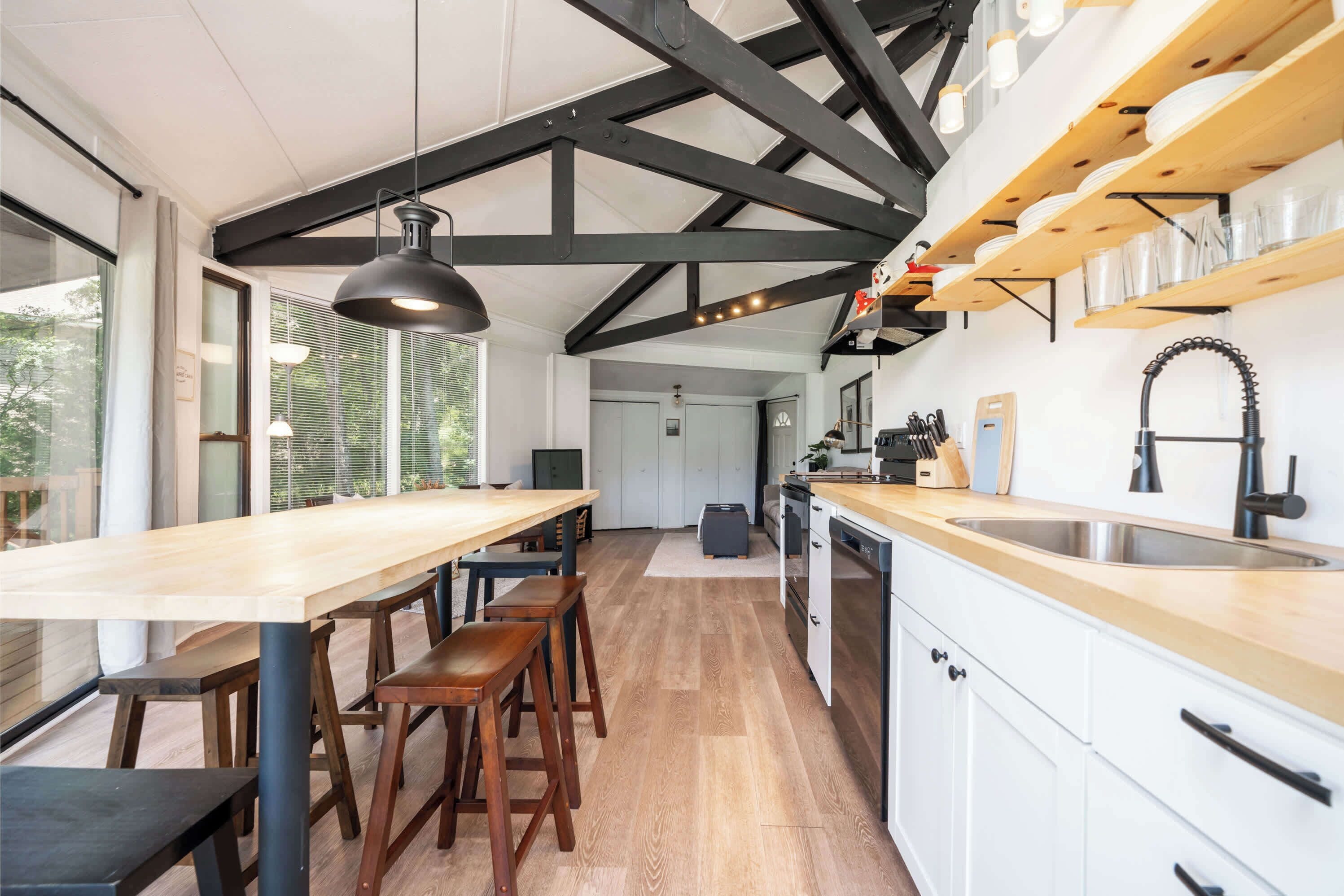 A modern kitchen with wooden countertops, a large island, and a black pendant light.