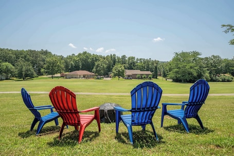 Outdoor seating with chairs and a table, a grassy area, and buildings in the background.. Unique Octagon Home near Hot Springs