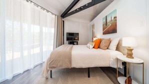A bedroom with a bed, a TV, a painting, and a lamp. - Unique Octagon Home near Hot Springs (Hot Springs)
