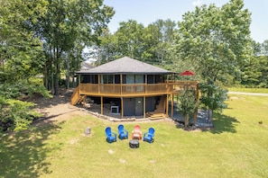 A two-story house with a deck, outdoor seating, and a covered area.