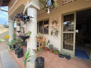 A covered outdoor area with potted plants, a door, and a tiled floor. - Artistic Oasis Near Bahai Temple & Fashion Studio, Free Parking & Garden Retreat (Kampala)