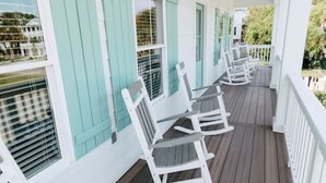 A covered porch with white rocking chairs and teal shutters. - Tybee Beach House & Private Pool (Tybee Island)