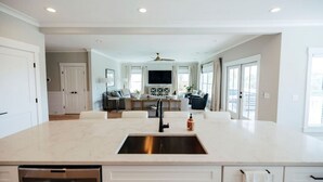 A spacious kitchen with a central island, built-in appliances, and a dining area with a large table and chairs. - Tybee Beach House & Private Pool (Tybee Island)