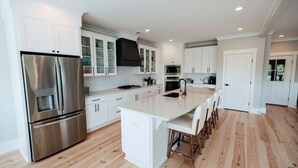 A modern kitchen with white cabinetry, stainless steel appliances, and a central island. - Tybee Beach House & Private Pool (Tybee Island)