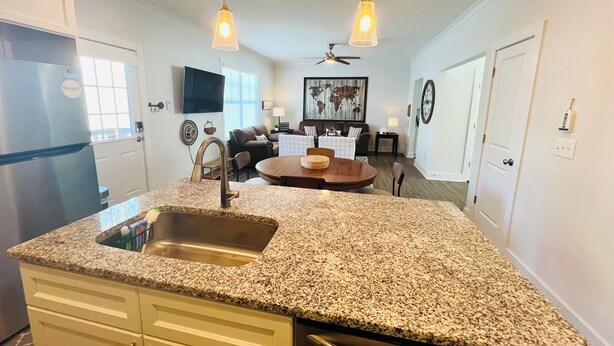 A kitchen with granite countertops, a stainless steel sink, and a built-in dishwasher. There is a dining area with a round table and chairs, and a ceiling fan above. - Downtown Villa - steps from the heart of Waxhaw (Waxhaw)