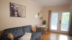A living room with a dark blue sofa, a fluffy rug, a glass coffee table, and a painting on the wall.